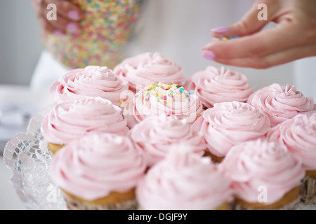 Frau mit Zucker Streusel Muffins dekorieren Stockfoto