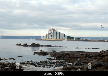 St. Michaels Mount bewölkten Hintergrund und Mount Bay, Felsen & Meer im Vordergrund Marizion Penzance Cornwall Lands End Halbinsel Stockfoto