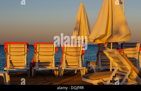 Liegestühle und Sonnenschirm Sonnenschirme im Licht der aufgehenden Sonne Stockfoto