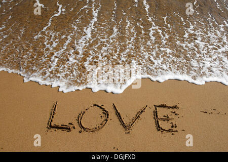 "Love" in den Sand am Strand geschrieben Stockfoto