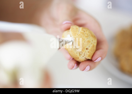 Frau Füllung Profiterole mit Sahne Stockfoto