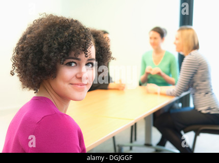 Junge Frau im Büro mit Kollegen im Hintergrund Stockfoto