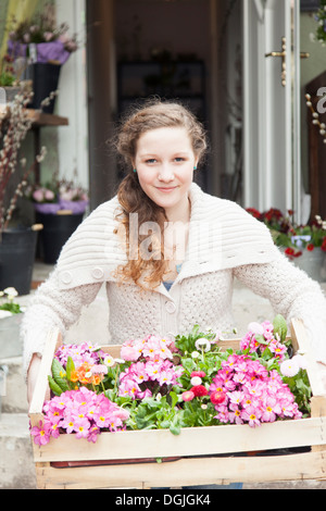 Porträt von Teenager-Mädchen tragen Kiste mit Blumen Stockfoto