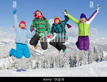 Gruppe junger Leute springen auf einer Skipiste, Salzburger Land, Flachau, Tirol, Österreich Stockfoto