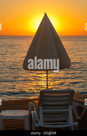 Chaise Lounge und Sonnenschirm Regenschirm im Hinblick auf Sonnenuntergang Stockfoto