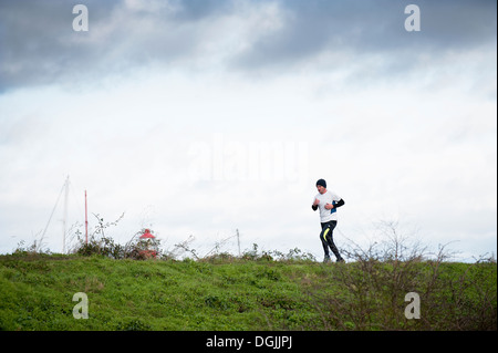 Ein Mann läuft entlang dem Deich bei Tollesbury Saltings. Stockfoto