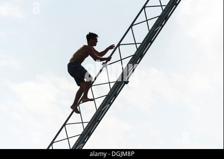 Die Silhouette eines Mannes, ein Strommast hinauf. Stockfoto