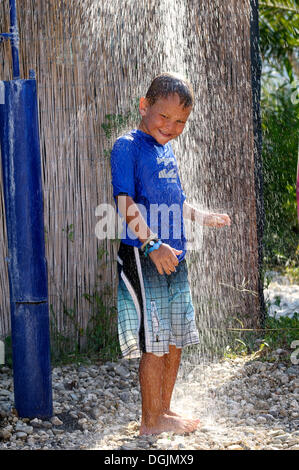 5-Year-Old Boy trug ein blaues T-shirt steht unter der laufenden Dusche in einem Garten, Vassiliki, Lefkas, Griechenland, Europa Stockfoto