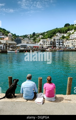 Ein Ehepaar und ihr Hund sitzt auf der Uferstraße in Looe. Stockfoto