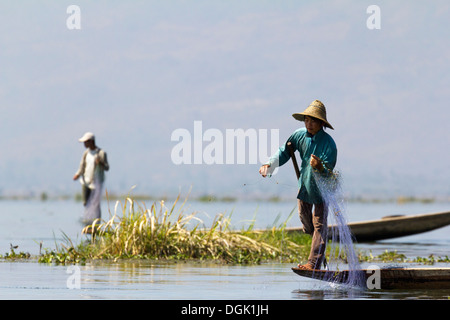 Fischer Bein Rudern und wirft seine Netze am Inle See in Myanmar. Stockfoto