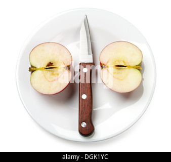 Hälften eines Apfels mit einem Messer auf einen Teller auf weißem Hintergrund Stockfoto