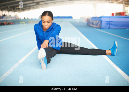 Junge Sportlerin sitzen am Boden, die Zehen zu berühren Stockfoto