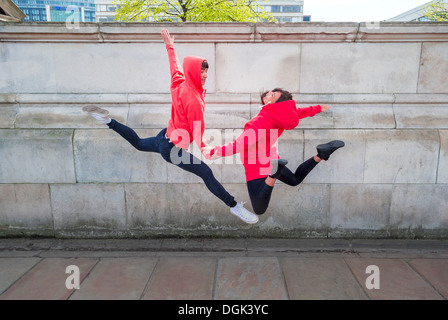 Junge männliche und weibliche Tänzer Mitte Luft in Stadt Stockfoto
