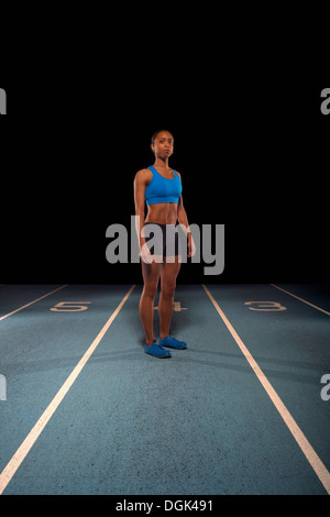 Junge Sportlerin stehend auf Rennstrecke Stockfoto
