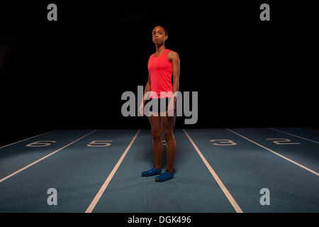 Junge Sportlerin stehend auf Rennstrecke Stockfoto
