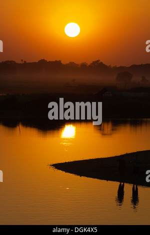 Spektakulären Sonnenuntergang über der Reisfelder und Pagoden aus U Bein Teakholz Brücke in Myanmar betrachtet. Stockfoto