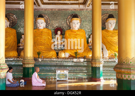 Eine Nonne und Frau beten vor Buddhas in der Shwedagon-Pagode in Yangon, Myanmar. Stockfoto