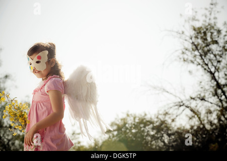 Mädchen in Engelsflügel und Gesichtsmaske Stockfoto