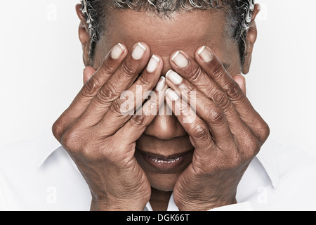 Ältere Frau, die ihre Augen bedecken Stockfoto