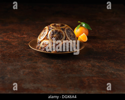 Christmas Pudding mit in Scheiben geschnittenen Orangen verziert Stockfoto