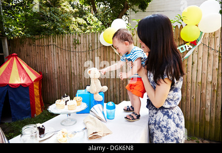 Mutter hält Baby Boy auf Tisch, auf weiches Spielzeug Stockfoto