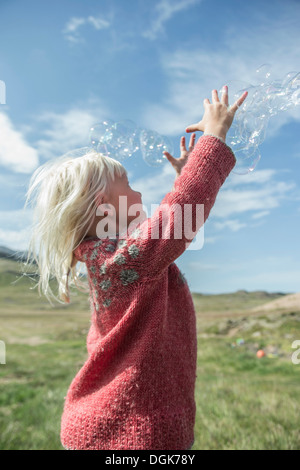 Junges Mädchen erreichen um Luftblasen zu fangen Stockfoto