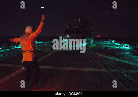 Der Bootsmann Mate 3. Klasse Taylor Baxley Signale an eine MH-60R Sea Hawk-Hubschrauber aus dem Sumpf Füchse der Hubschrauber Maritime S Stockfoto