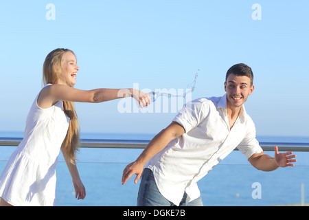 Frau wirft Wasser zu ihrem Freund mit dem Himmel im Hintergrund Stockfoto