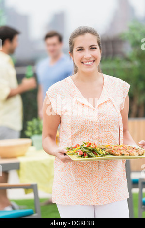 Frau mit Tablett mit Essen im Garten Stockfoto