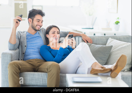 Paar erholsame auf Sofa mit Handys Stockfoto