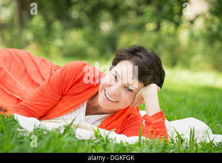 Reife Frau liegend auf dem Rasen Stockfoto