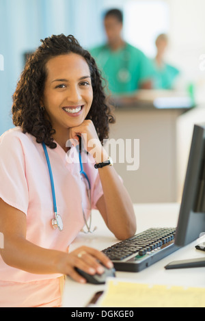 Porträt von lächelnden Ärztin arbeiten am Schreibtisch im Krankenhaus Stockfoto