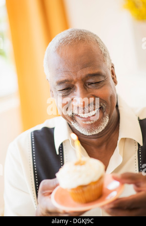 Porträt des Mannes halten Cupcake mit Kerze Stockfoto