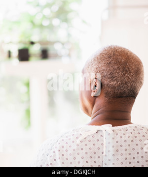 Rückansicht des Patienten tragen OP-Kittel und Blick durch Fenster Stockfoto