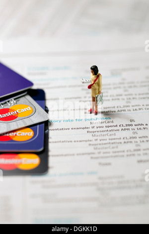 Spielzeugfigur einer Frau stand neben Mastercard Kreditkarten auf einer Seite einer finanziellen Zeitung. Stockfoto