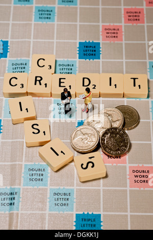 Fliesen auf einem Scrabble-Brett mit einem Spielzeug-Mann und Frau und englische Pfund-Münzen. Stockfoto