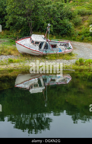 Ein gestrandeter, aufgegeben und Fäulnis altes Fischerboot und seine Reflexion in das Wasser des kleinen Hafens von Quidi Vidi. Stockfoto