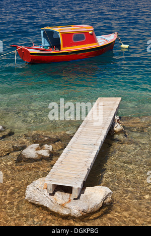 Ein einzelnes rotes Boot und hölzernen Steg auf der Insel Symi. Stockfoto