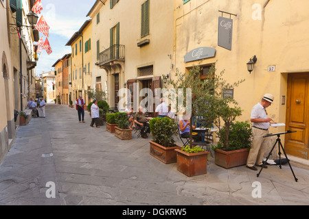 Menschen sitzen an Tischen genießen Sie einen Drink am Nachmittag vor einem Restaurant in San Quirico D'Orcia. Stockfoto