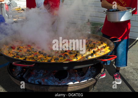 Eine große Pfanne Paella Kochen auf Holzfeuer auf einem Meeresfrüchte-Festival in Santa Barbara, Kalifornien mit Cook Muscheln hinzufügen. Stockfoto