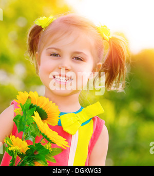 Closeup Portrait der niedliche kleine Mädchen holding Bouquet von frischen gelben Sonnenblumen im Freien, Sommerurlaub, Entspannung auf Hinterhof Stockfoto