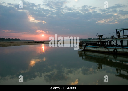 Ein Holzboot ist auf dem Mekong River angedockt, während die Sonne, über die Insel Koh Paen, Kompong Cham, Kambodscha untergeht. Stockfoto