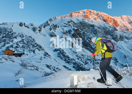 Mann Schneeschuhwandern in Richtung Carl-von-stahl Haus am Torrener Joch, Sonne auf hohes Brett Berg, eine Hütte aus der Stockfoto