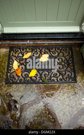 Buntes Herbstlaub, die auf eine willkommene Matte vor einer Hütte Tür mit den Worten willkommen auf die Matte gefallen haben Stockfoto