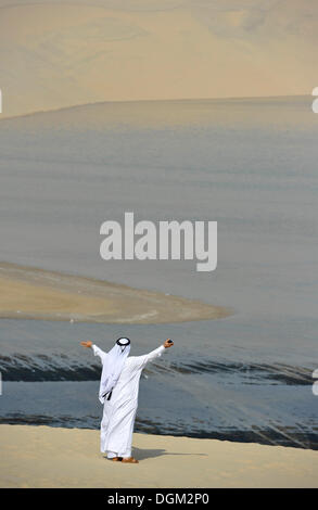 Qatari in traditioneller Kleidung mit Gutra, vor Khor Al Udeid Strand, Khor El Deid, Binnenmeer, Wüste Wunder von Katar Stockfoto