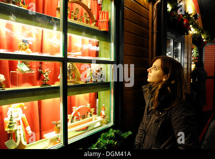 Junge Frau betrachten Spielzeuge aus dem Erzgebirge in einem Schaufenster, Weihnachtsmarkt, Stuttgart, Baden-Württemberg Stockfoto