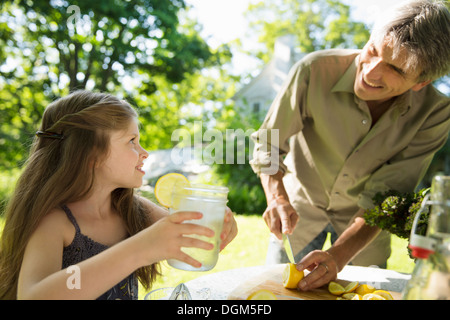 Auf dem Bauernhof. Kinder und Erwachsene gemeinsam. Ein Mädchen und ein erwachsener Mann Limonade zu machen. Schneiden Sie frisches Obst. Stockfoto