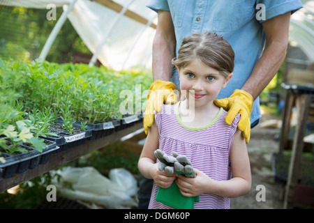 Bauernhof Kinder Mann Erwachsene gemeinsam Kind Gartenhandschuhe stehend neben Bank junge Setzling Pflanzen Stockfoto