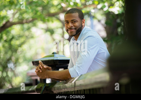 Sommer. Ein Mann in einem weißen Hemd, stützte sich auf ein Geländer. Stockfoto