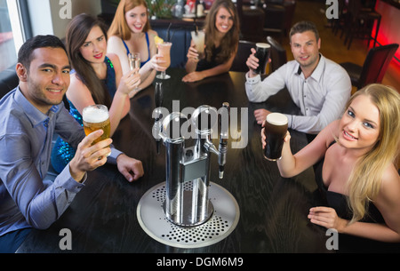 Attraktive Freunde Anhebung Gläser, lächelnd in die Kamera Stockfoto